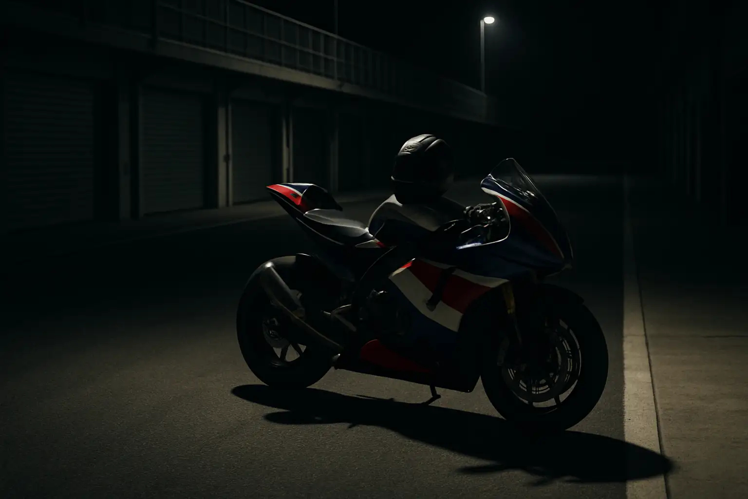 A MotoGP racing motorcycle on track with an empty pit lane in the background
